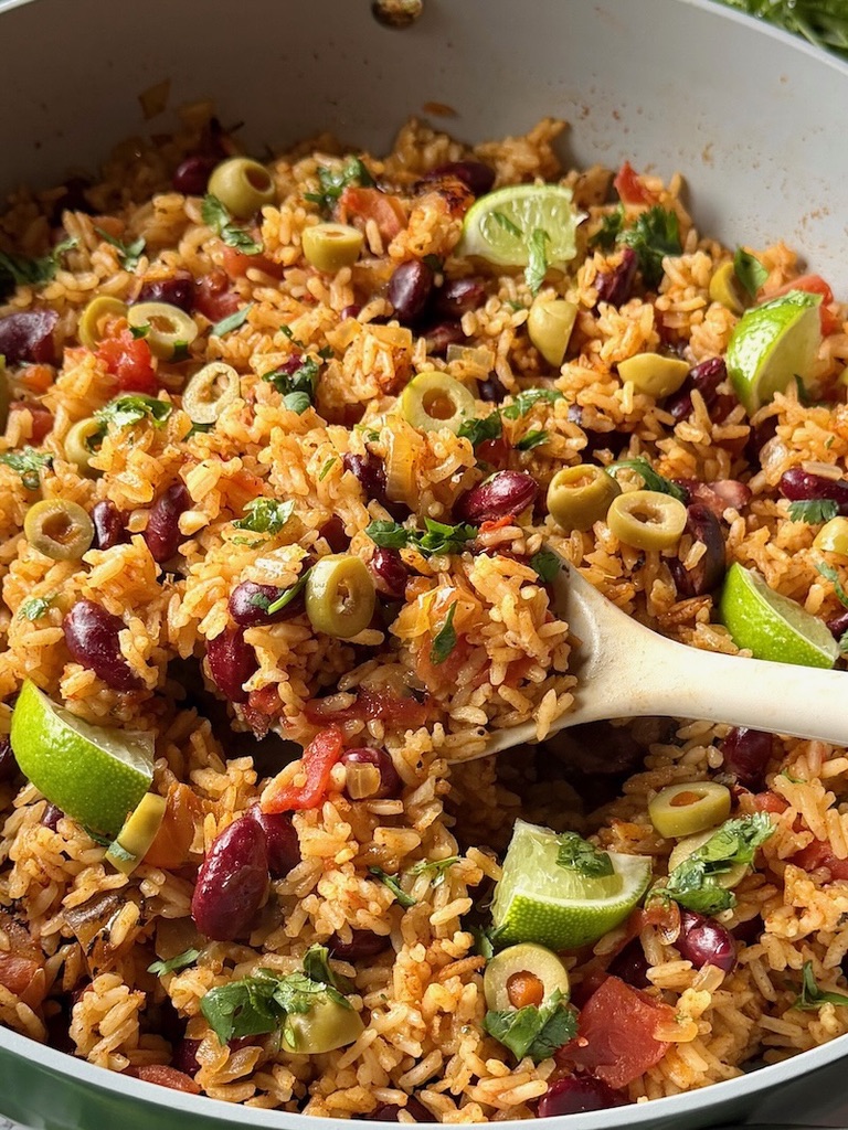 Spanish rice and beans in a skillet with a serving spoon