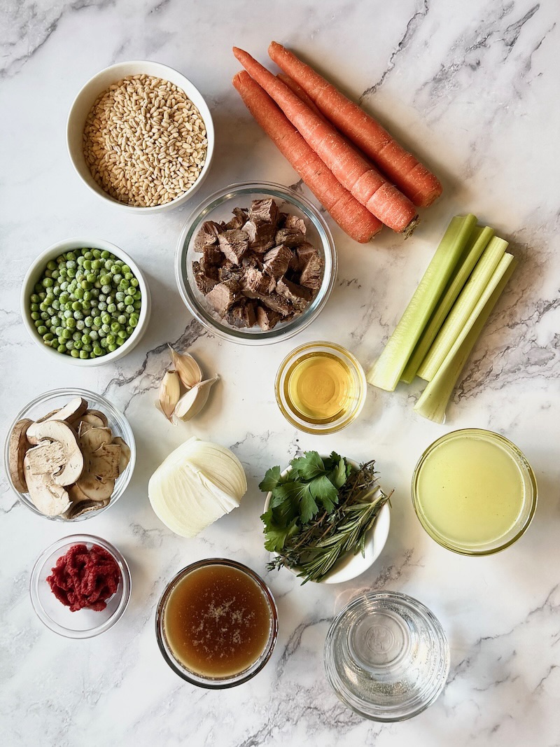 Ingredients displayed for beef barley stew. leftover beef, pearl barley, carrots, celery, onions, garlic, mushrooms, cooking liquid, chicken broth, parsley, tomato paste, fresh herbs, salt and pepper.
