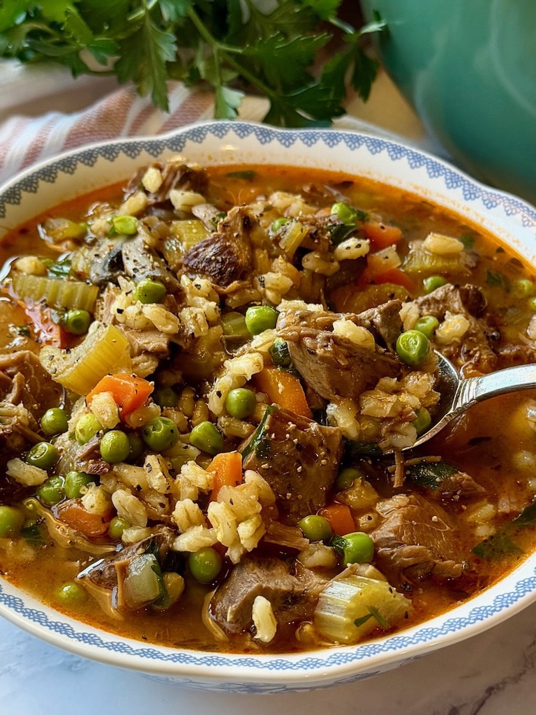 Serving bowl with beef barley stew and a spoon