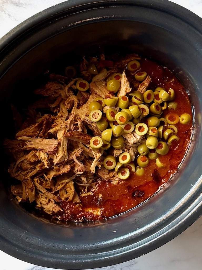 Green olives, pork, and red wine vinegar back in the slow cooker.