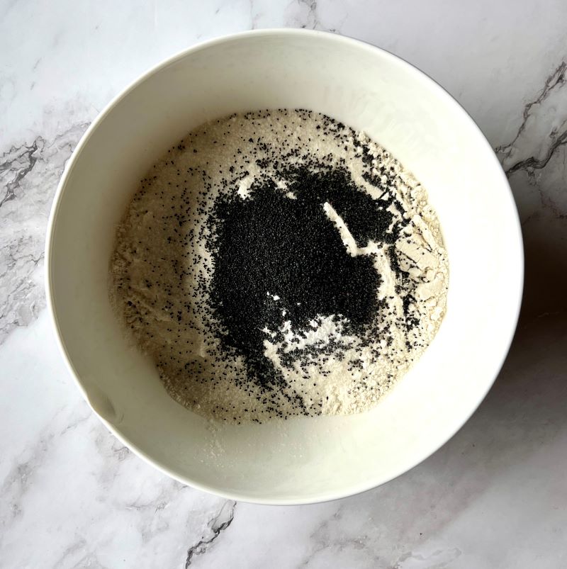 Dry ingredients mixed in a small bowl. Flour, sugar, baking soda, baking powder, salt, and poppy seeds. 