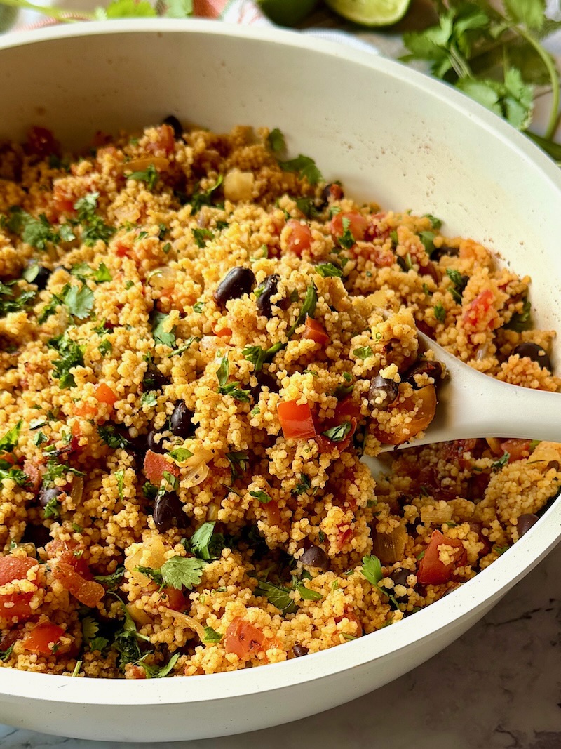 Mexican couscous in a skillet with a serving spoon