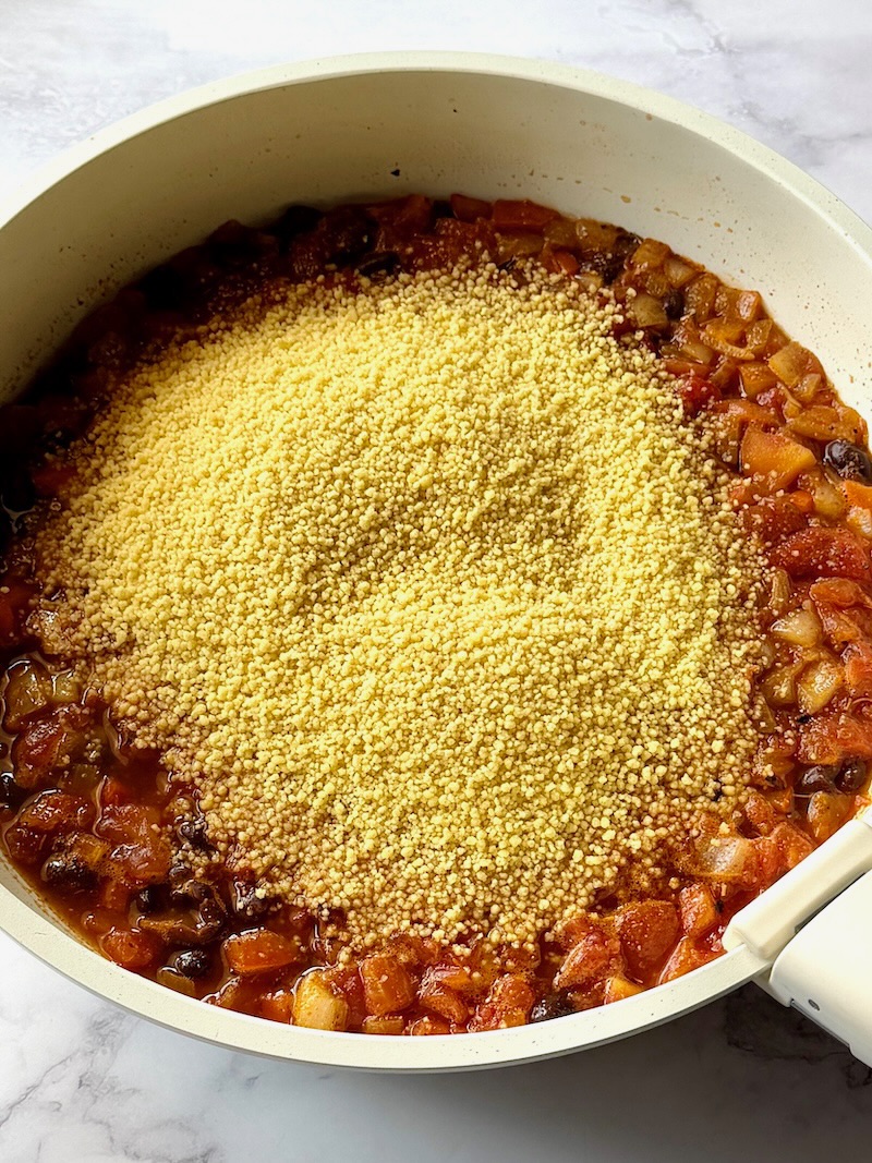 Uncooked couscous added to the skillet.