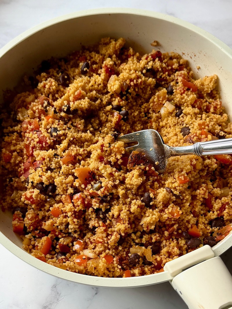 Fluffing the cooked couscous with a fork