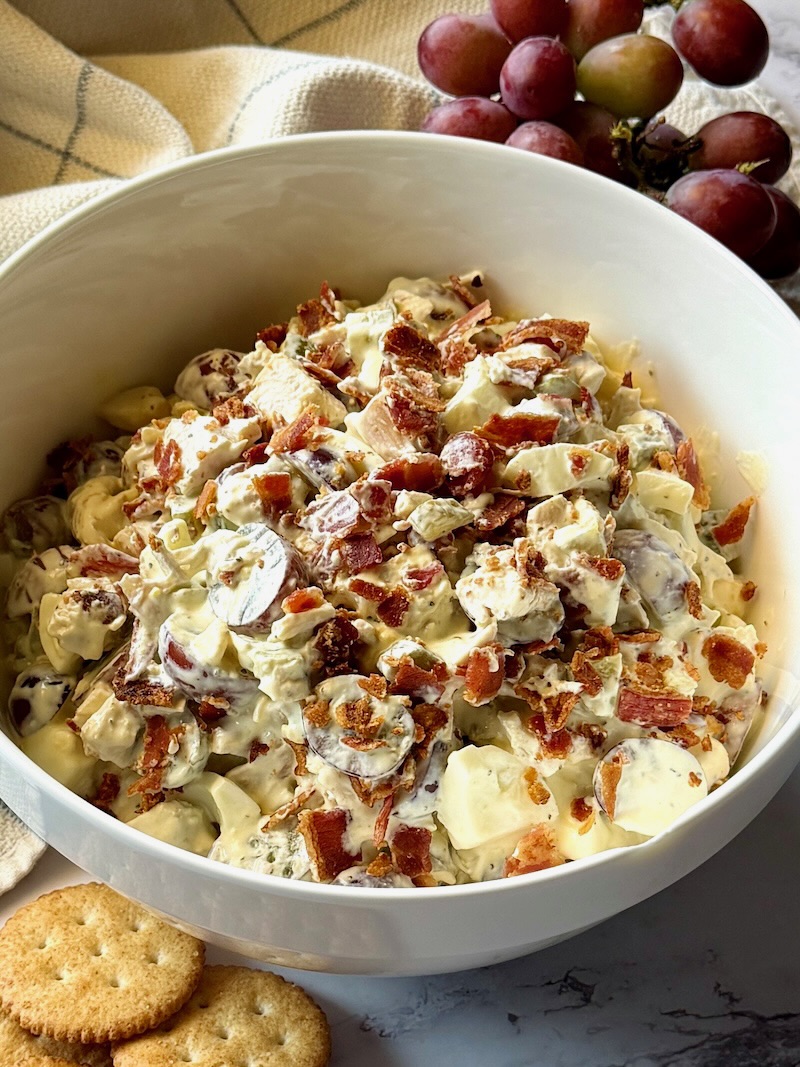 Easy chicken salad with bacon in a serving bowl with crackers and grapes on the side.