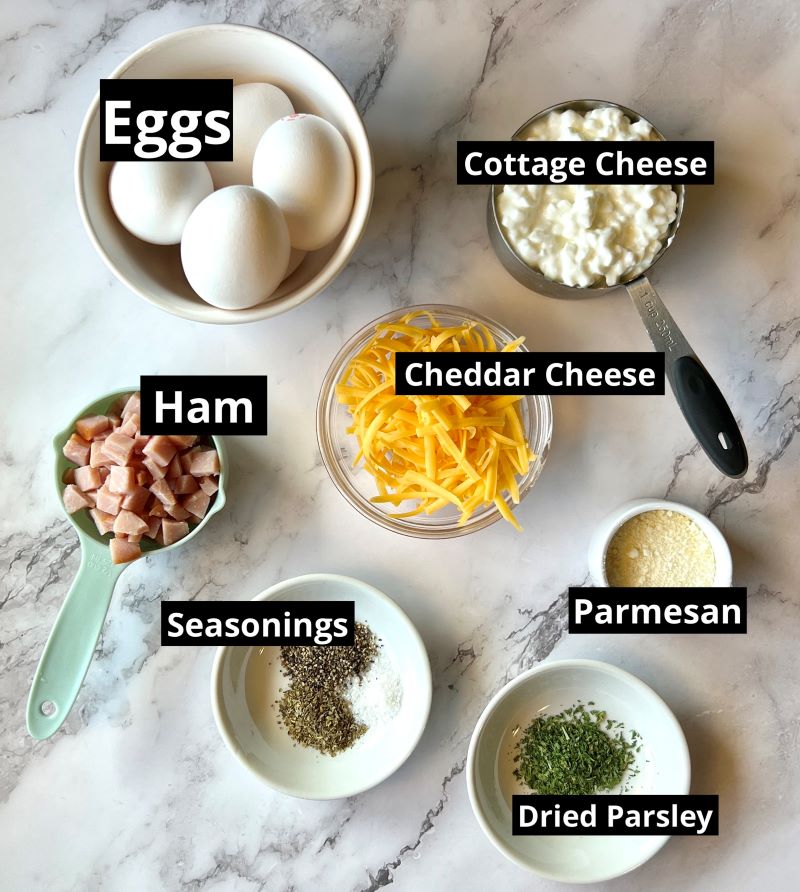 Ingredients displayed for egg bites. Eggs, cottage cheese, diced ham, shredded cheddar cheese, parmesan, seasonings. 