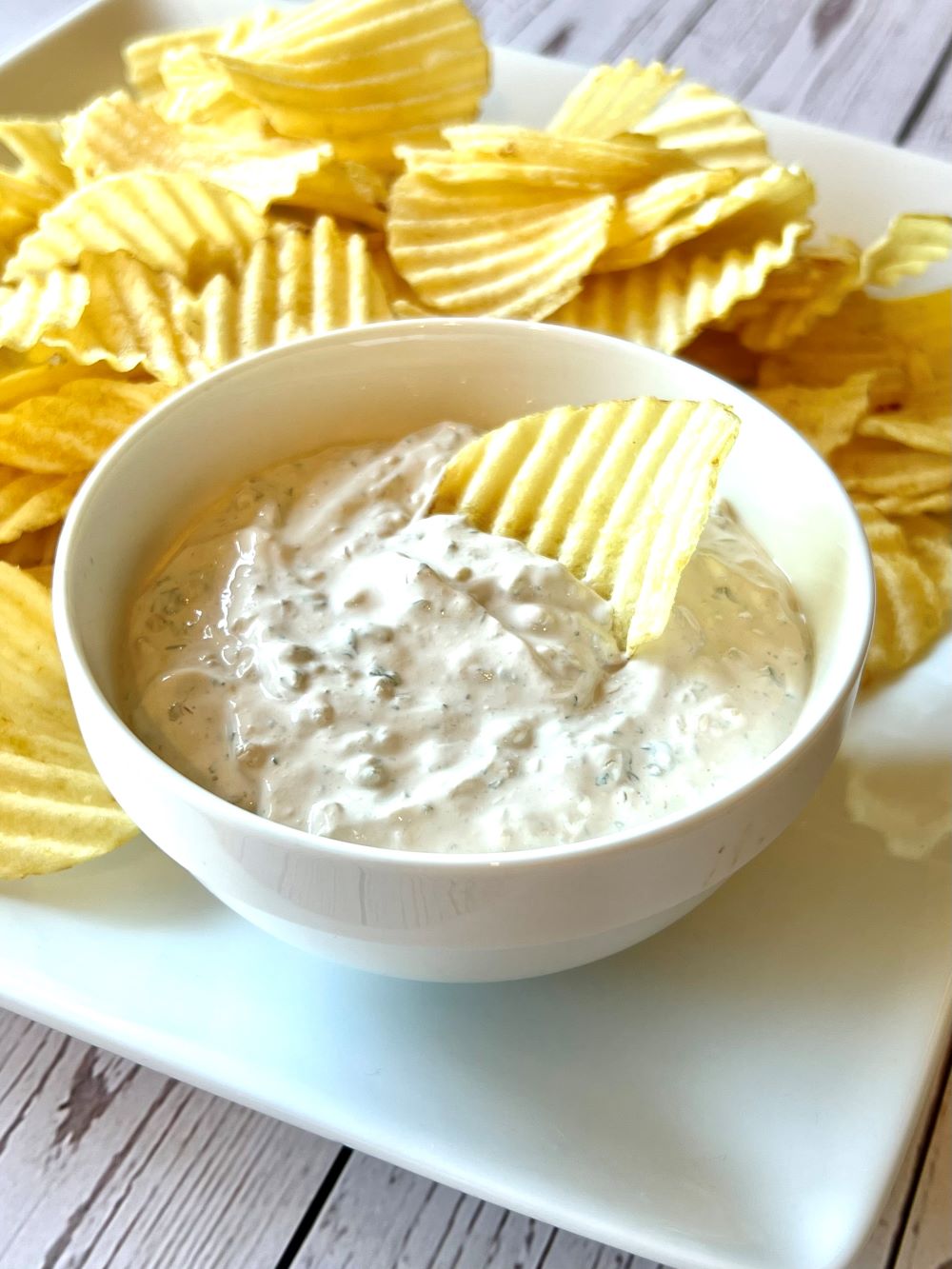 Plate with potato chips and chip dipped in French onion dip