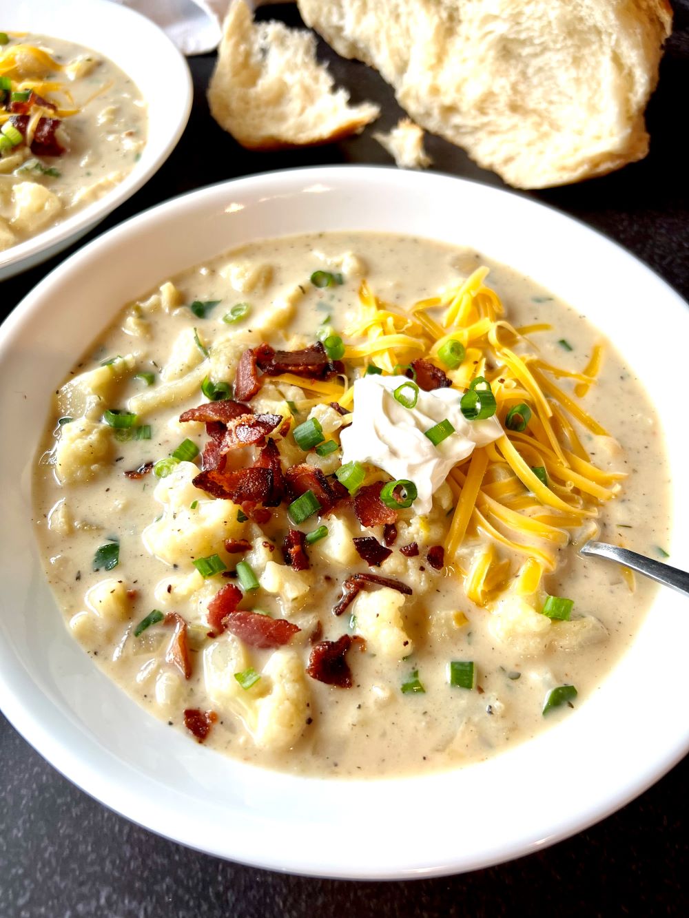 Bowl with cauliflower soup topped with cheese, bacon, sour cream and green onion