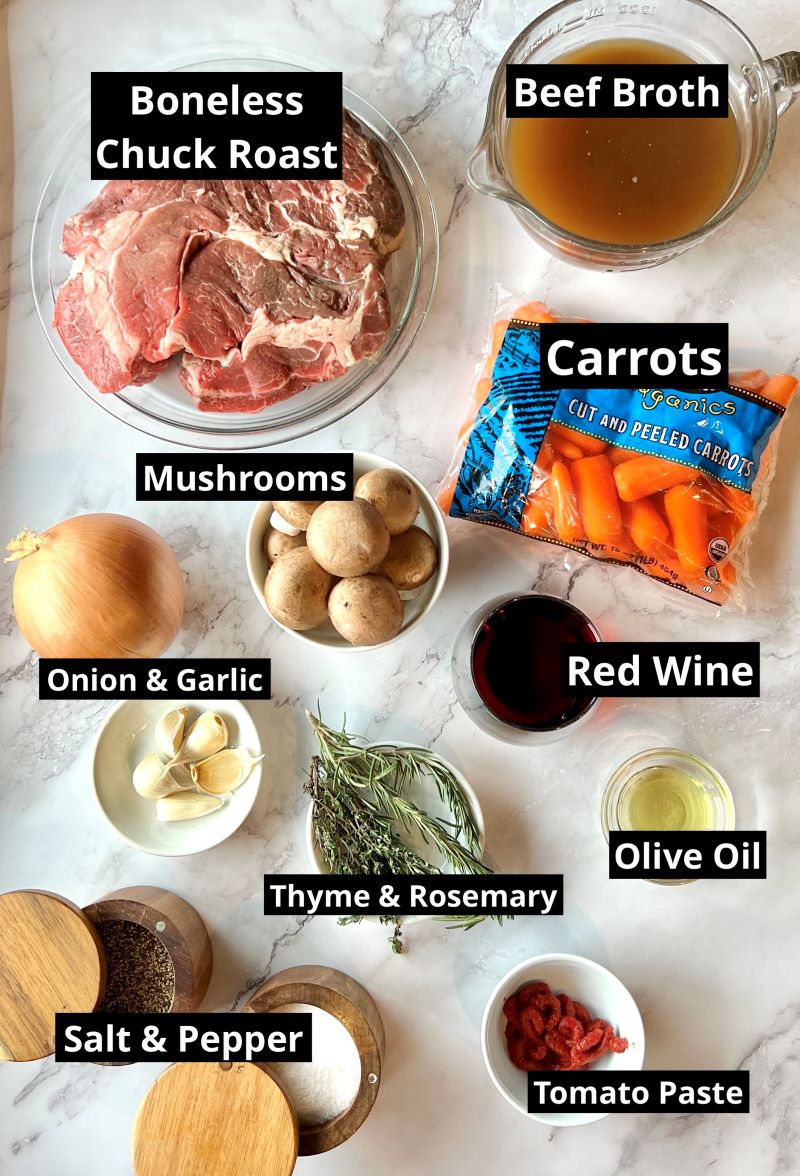 Ingredients for braised pot roast with mushrooms and carrots. Boneless chuck roast, beef broth, red wine, mushrooms, onions, garlic, olive oil, fresh thyme and rosemary, tomato paste, salt and pepper. 