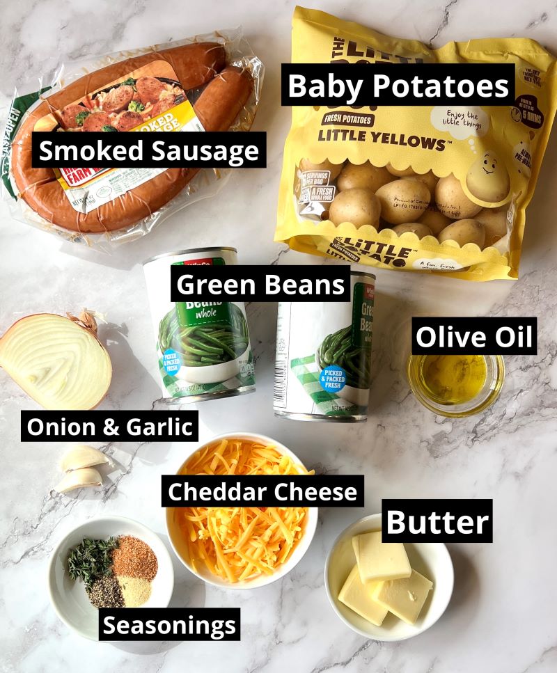 Ingredients for smoked sausage potato casserole. Smoked sausage rope, baby potatoes, canned green beans, olive oil, onions, garlic, butter, cheddar cheese, thyme, garlic powder, salt, pepper, Creole seasoning. 