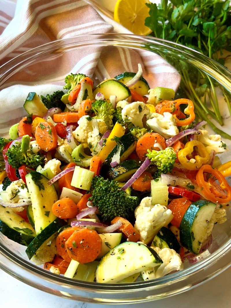 Marinated vegetable salad in a bowl with a serving spoon.