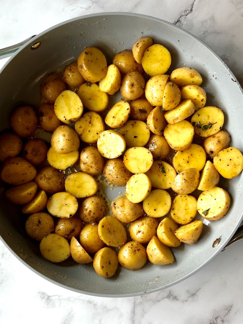 Seasoned potatoes browning in a large skillet. 