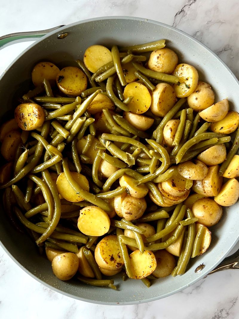 Potatoes, Creole seasoning, garlic powder, salt, pepper, and canned green beans sauté in a large skillet. 