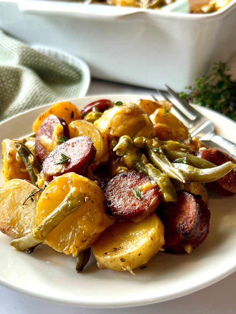 A serving plate with smoked sausage and potato casserole.