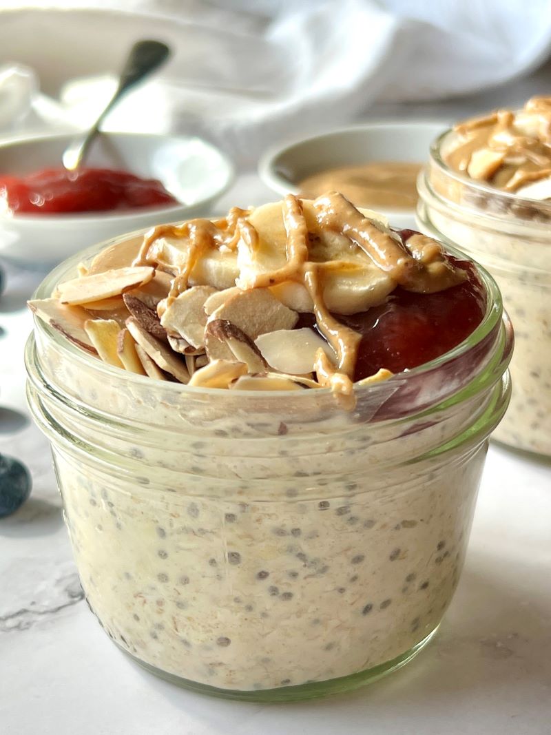 Overnight oats in a mason jar topped with peanut butter, strawberry jelly, and toasted almonds. 