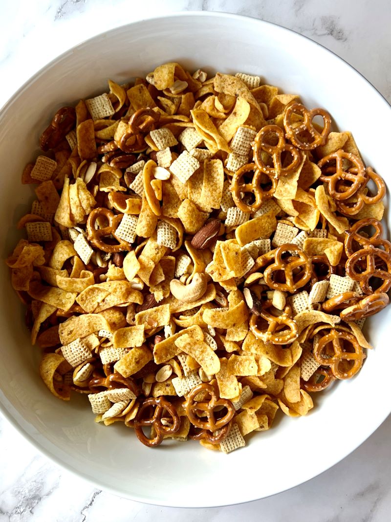 Fritos mix combined in a large bowl with rice Chex, pretzels, and mixed nuts. 
