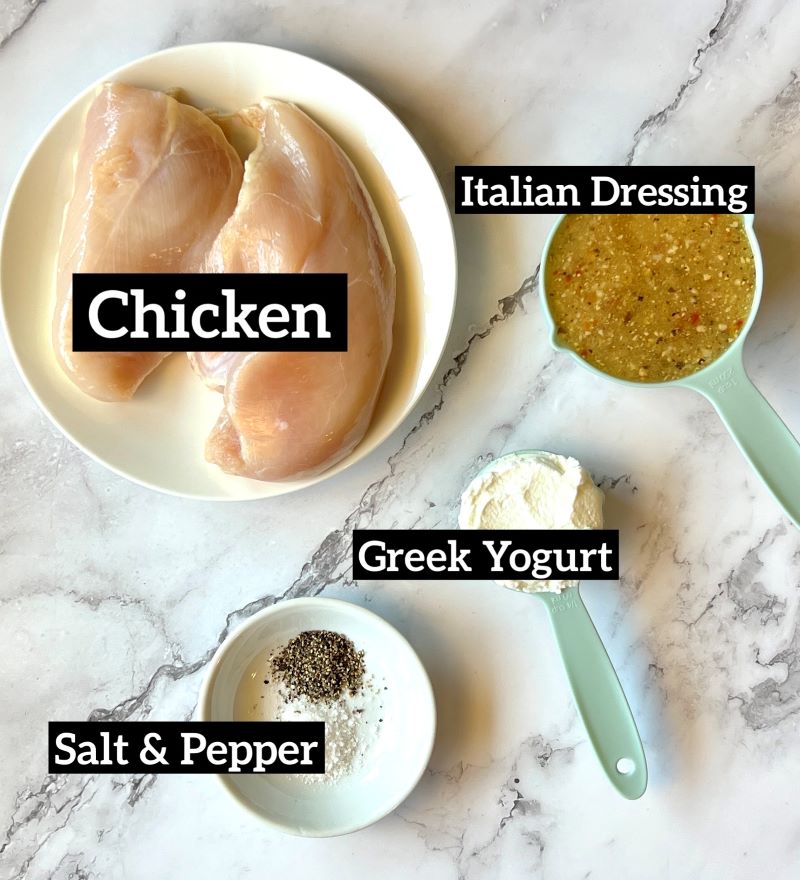 Ingredients set out for grilled chicken kabobs. Chicken breast, Italian dressing, Greek yogurt, salt and pepper. 