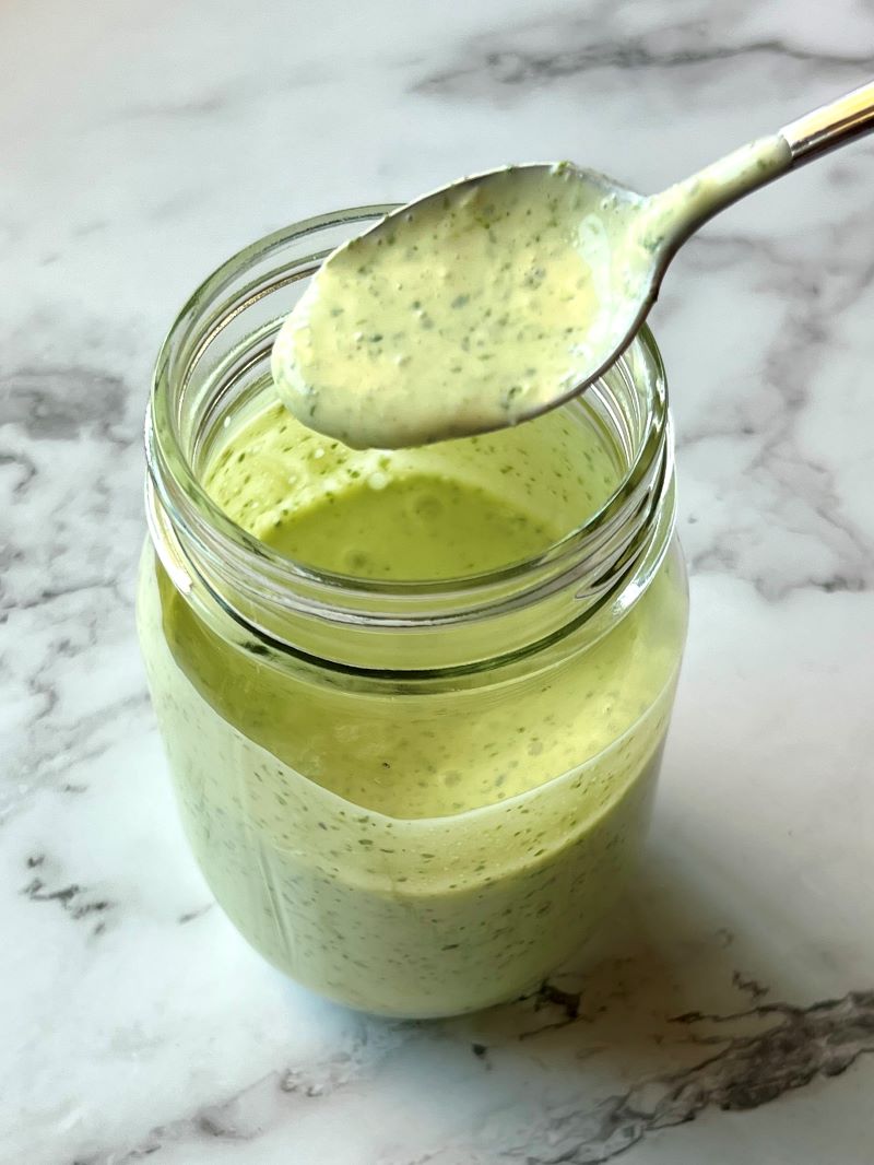 Creamy cilantro dressing mixed in a mason jar with a spoon.