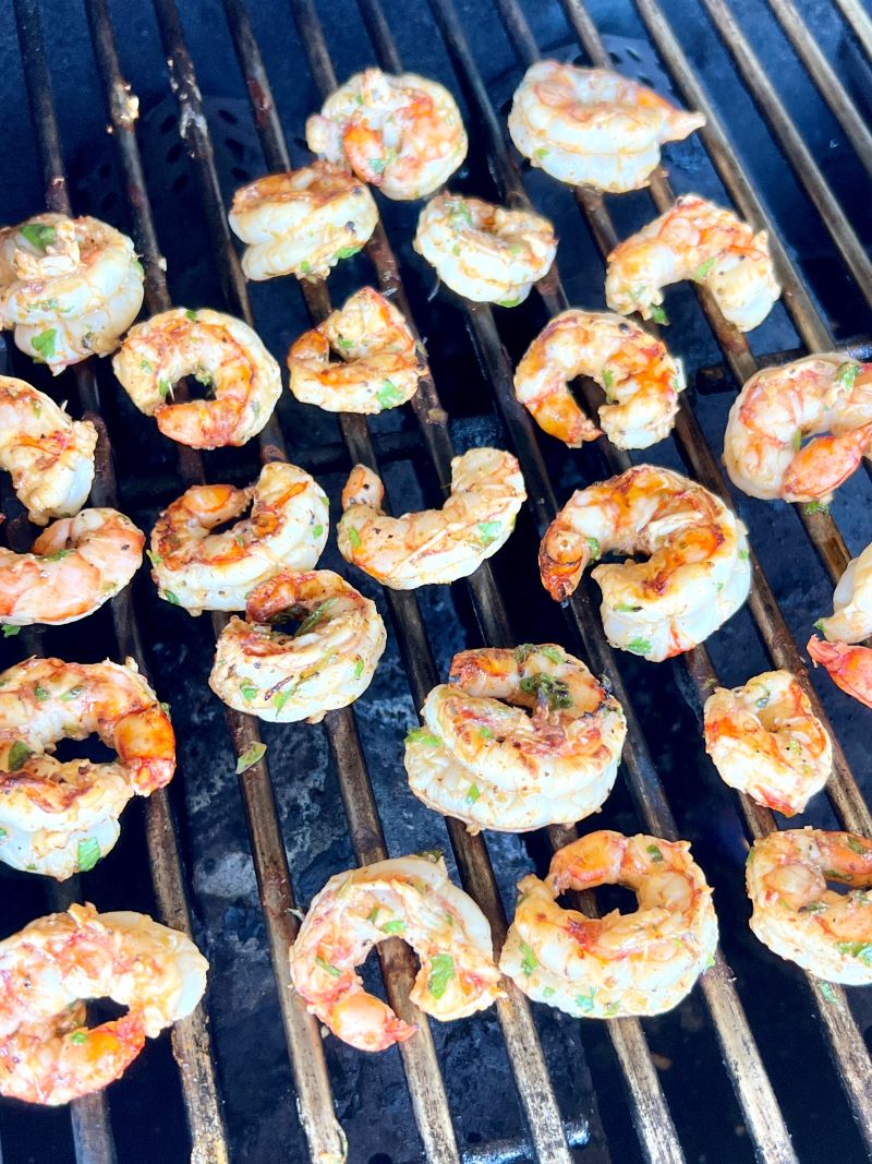 Marinated shrimp cooking on an outdoor grill.