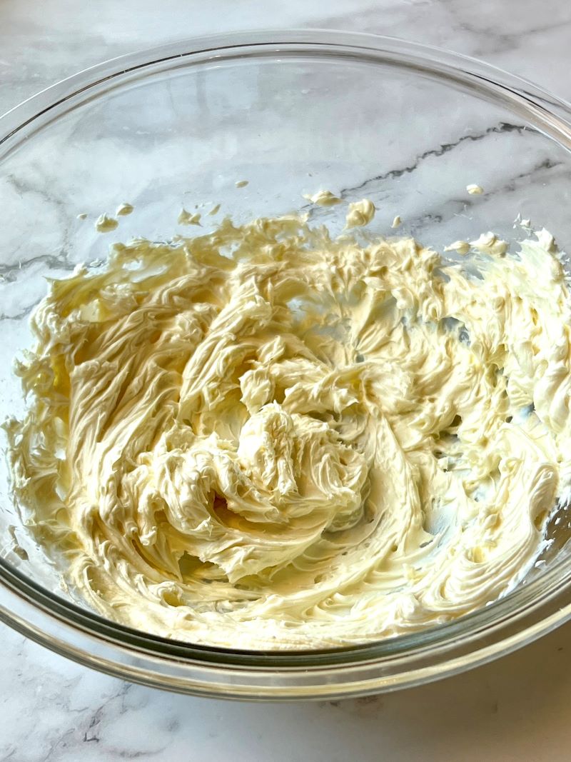 Cream cheese in a bowl whipped with powdered sugar and vanilla extract. 