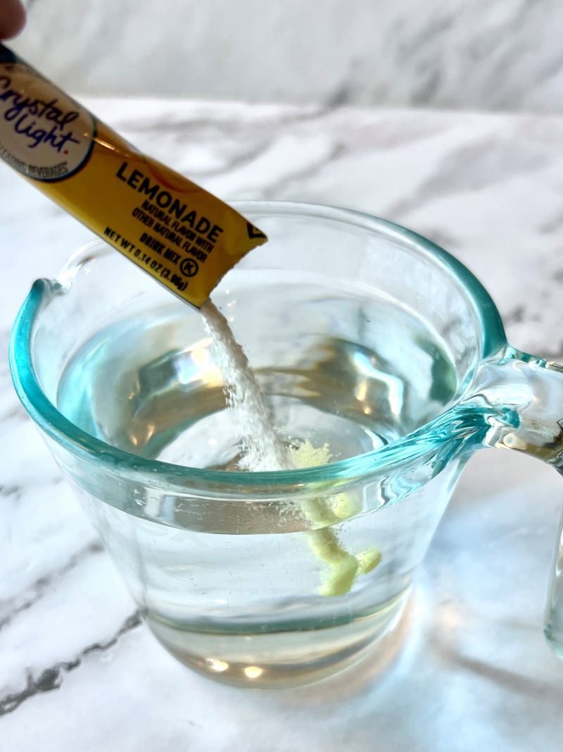 Crystal light lemonade mixed with water in a measuring cup.