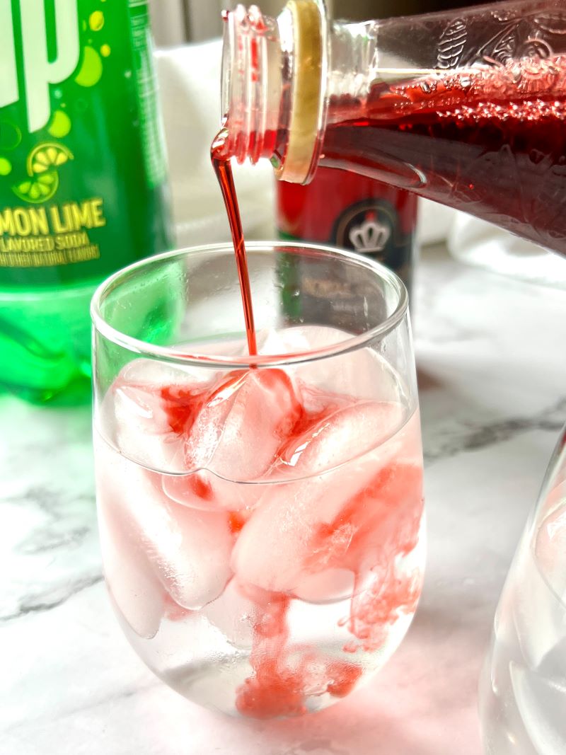 Clear glass filled with ice, 7-up, and splashing in grenadine. 