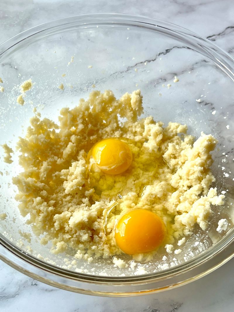 Butter, sugar, eggs, and almond extract mixed in a separate bowl