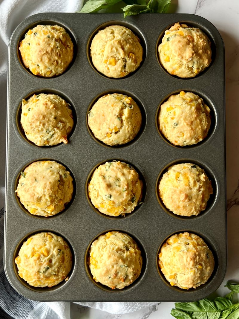 Baked Cheesy corn muffins with basil in a muffin pan.