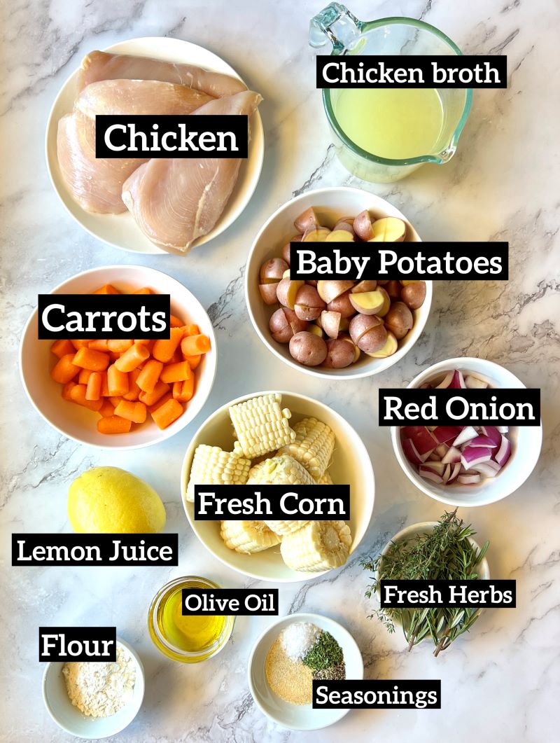 Ingredients displayed for slow cooker summer chicken Chicken breast, chicken broth, baby red potatoes, carrots, fresh corn on the cob, red onion, lemon juice, fresh herbs, olive oil, seasonings, flour. 