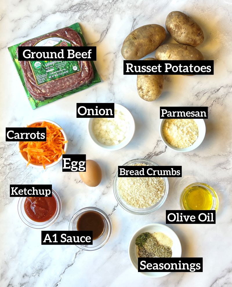 Ingredients displayed for sheet pan mini meatloaf and potatoes. Lean ground beef, russet potatoes, onion, carrots, parmesan, egg, bread crumbs, ketchup, A1 steak sauce, olive oil. seasonings. 