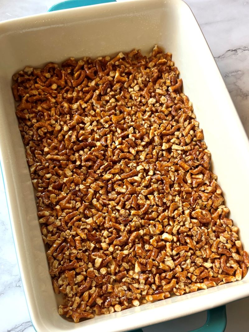 Crushed pretzels mixed with melted butter and sugar then spread in a baking dish.