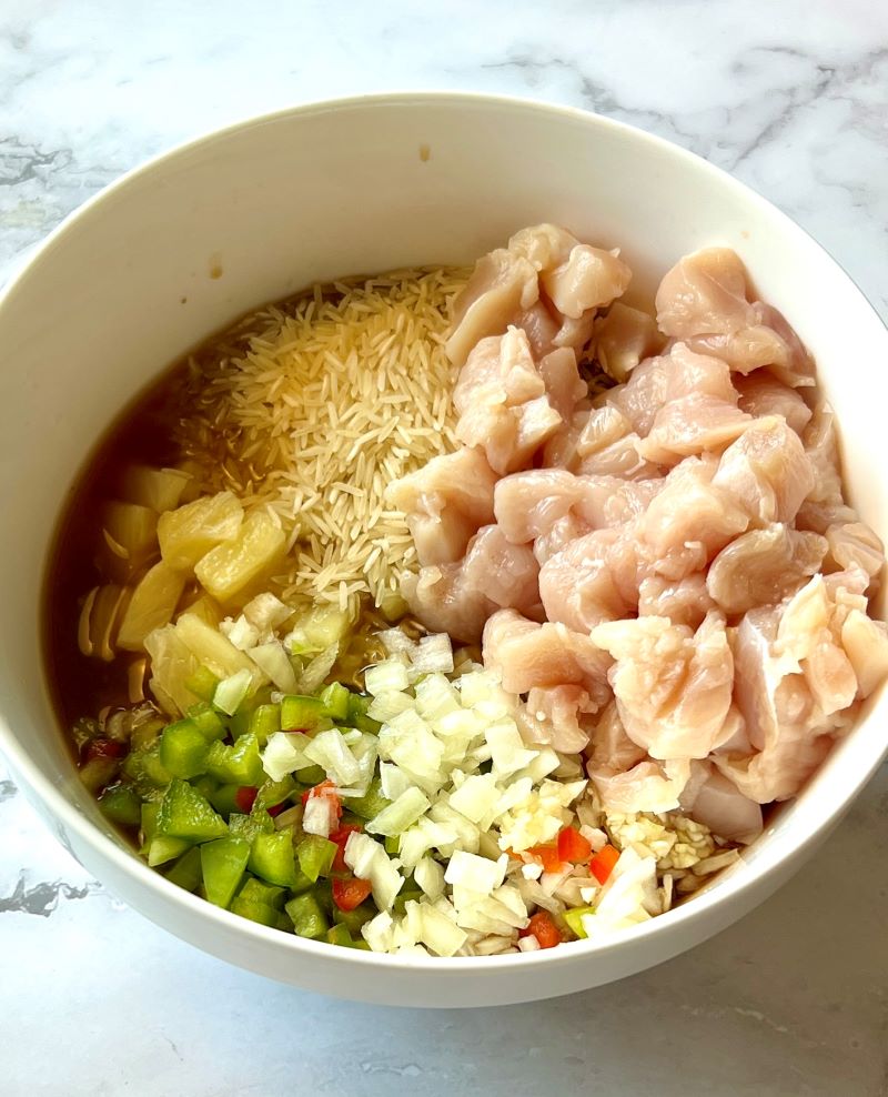 Chicken, pineapple, veggies, rice, and sauce in a bowl.