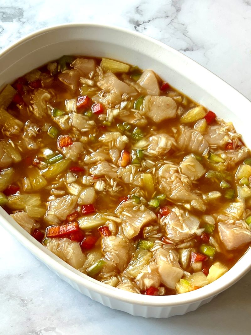 Pineapple chicken ingredients added to a baking dish.