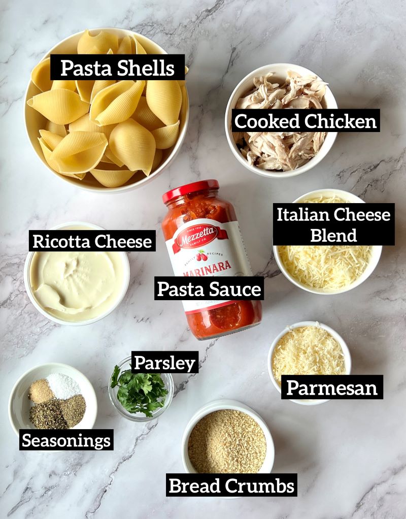 Ingredients for chicken parmesan stuffed shells. Jumbo pasta shells, cooked shredded chicken, ricotta cheese, pasta sauce, Italian cheese blend, parmesan cheese, fresh parsley, bread crumbs, seasonings.
