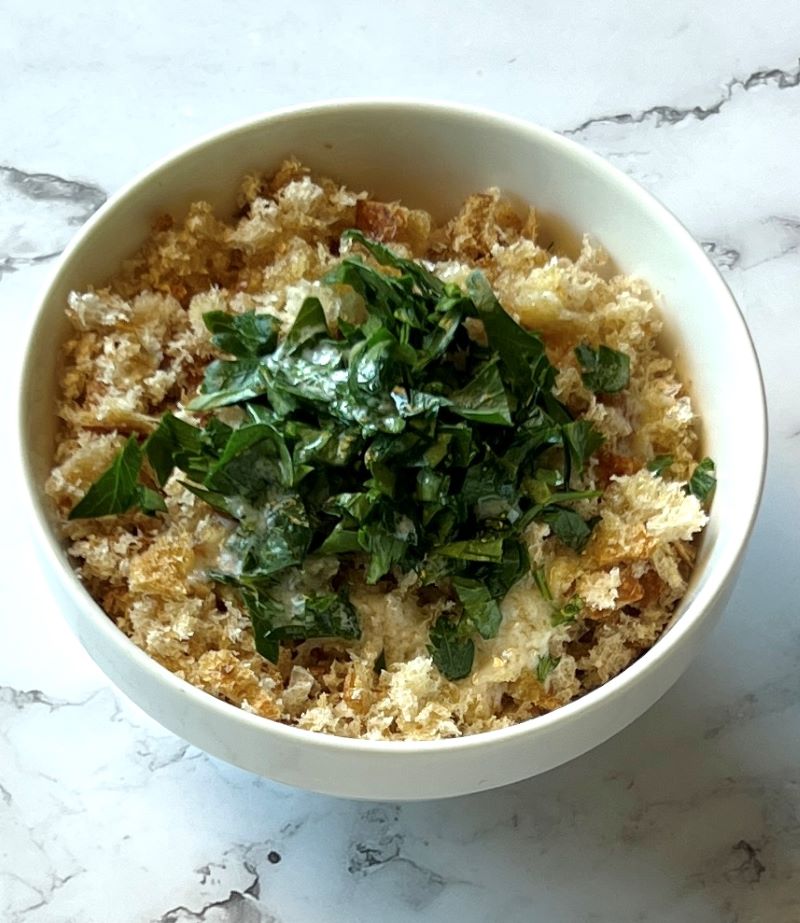 Breadcrumbs in a small bowl with melted butter and fresh parsley. 
