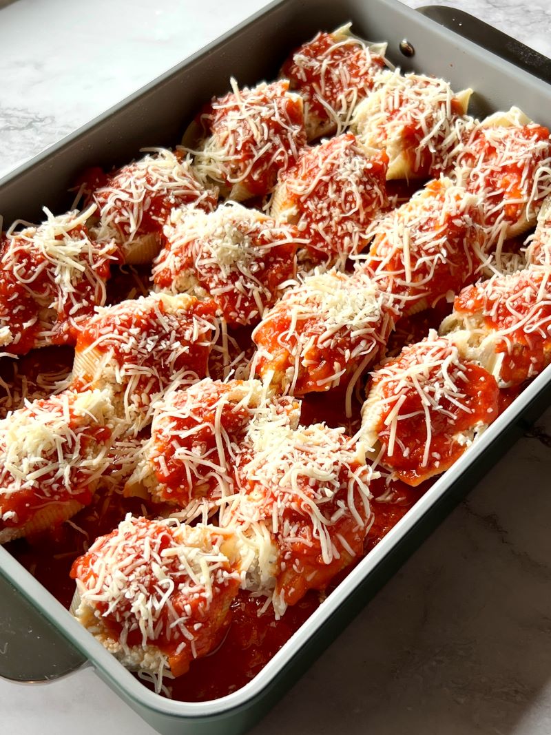Cooked pasta shells stuffed with chicken and cheese in a baking dish