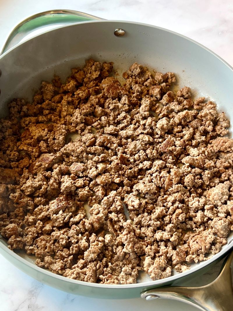 Ground beef cooked and crumbled in a large skillet.