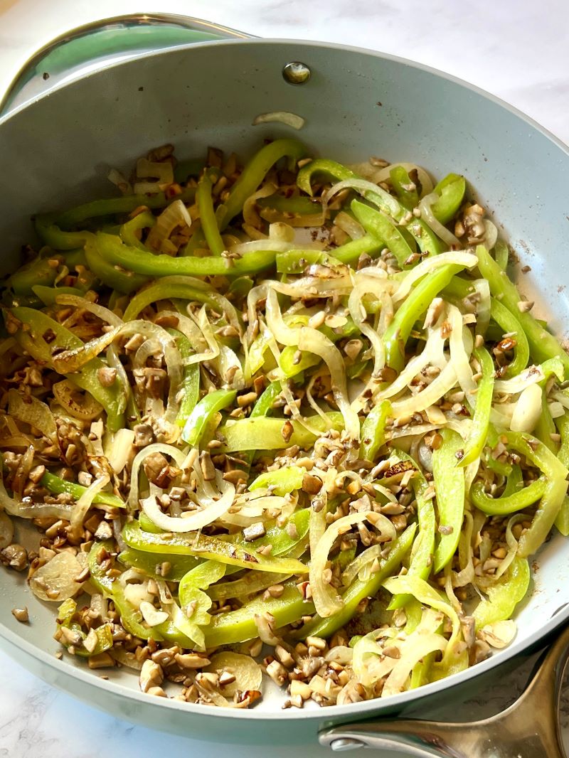 Bell peppers, onions, and mushrooms sautéed in a large skillet. 