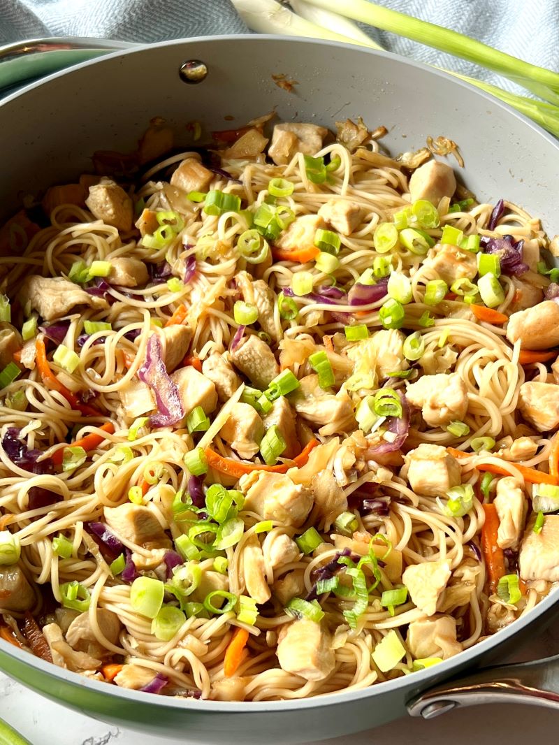 Chicken chow Mein recipe with green onions in a large skillet. 