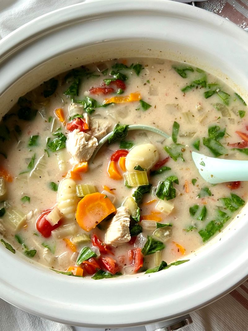 Slow cooker chicken gnocchi soup with a ladle.