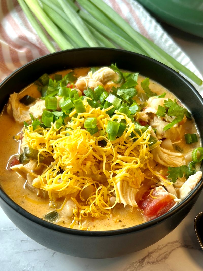 Bowl of creamy buffalo chicken soup topped with shredded cheese, green onions, and cilantro. 