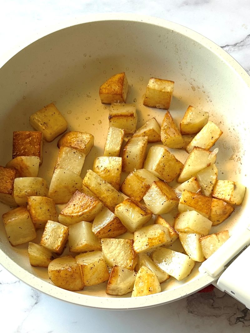 Cubed potatoes browned in a skillet.