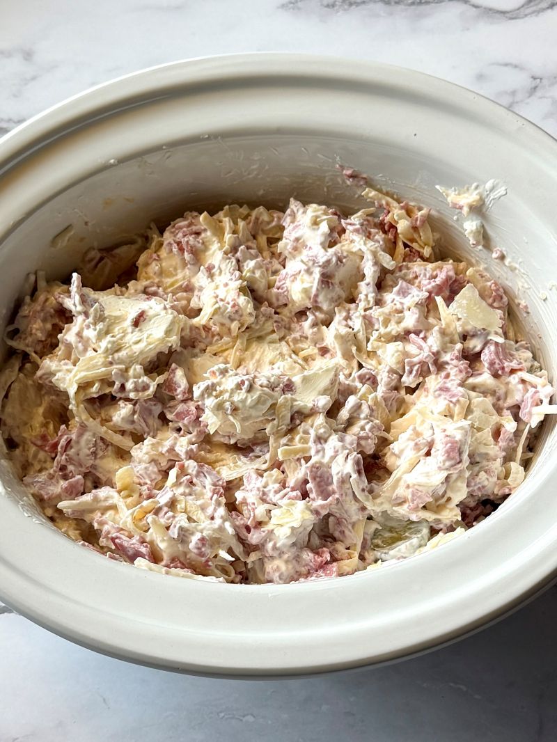 Reuben dip ingredients combined in a slow cooker. 