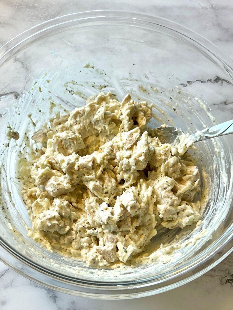 Filling for rollups in a mixing bowl. Chicken, cheese, alfredo sauce, and seasonings.