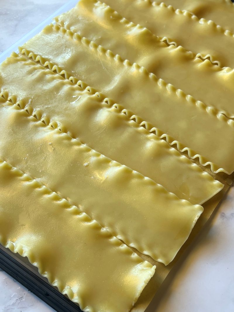 Cooked lasagna sheets lined on parchment paper. 