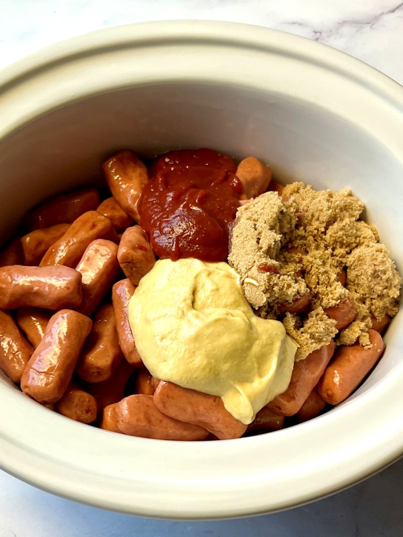 Little smokies in the slow cooker with brown sugar, maple syrup, ketchup, Dijon mustard, and Worcestershire.