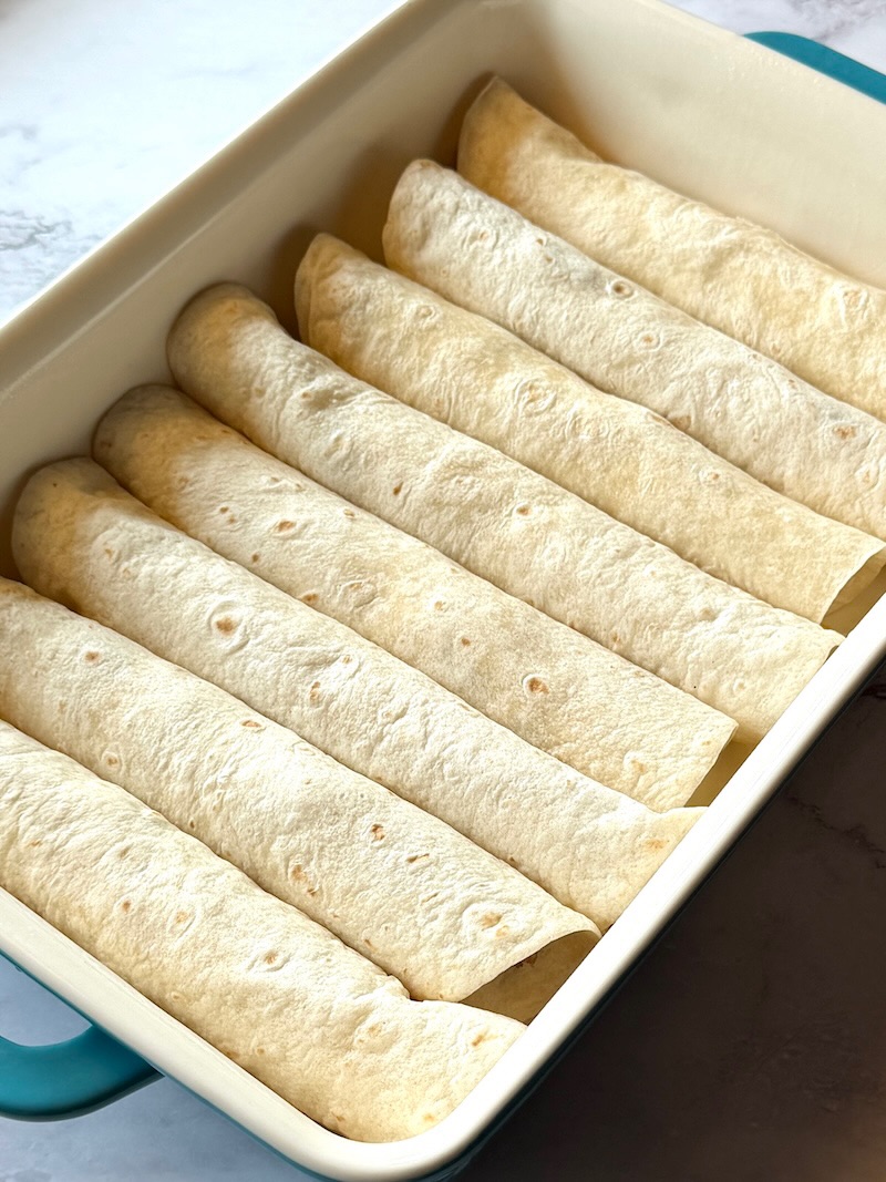 Enchiladas rolled up in a baking dish.
