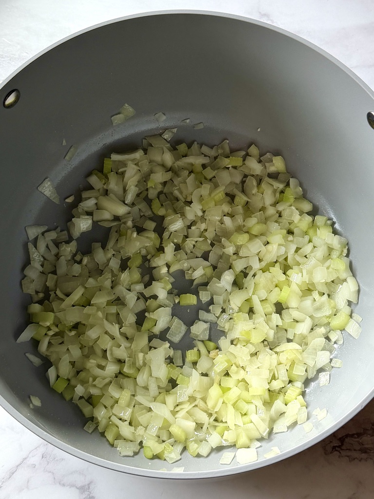 Onions and celery sautéing in a soup pot.