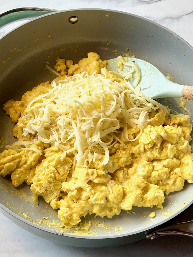 Scrambled eggs cooked in a pan with cheese.