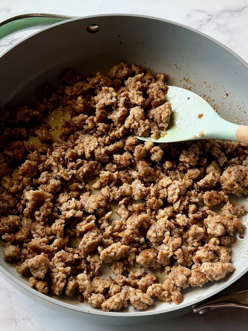 Cooked breakfast sausage crumbled in a pan.